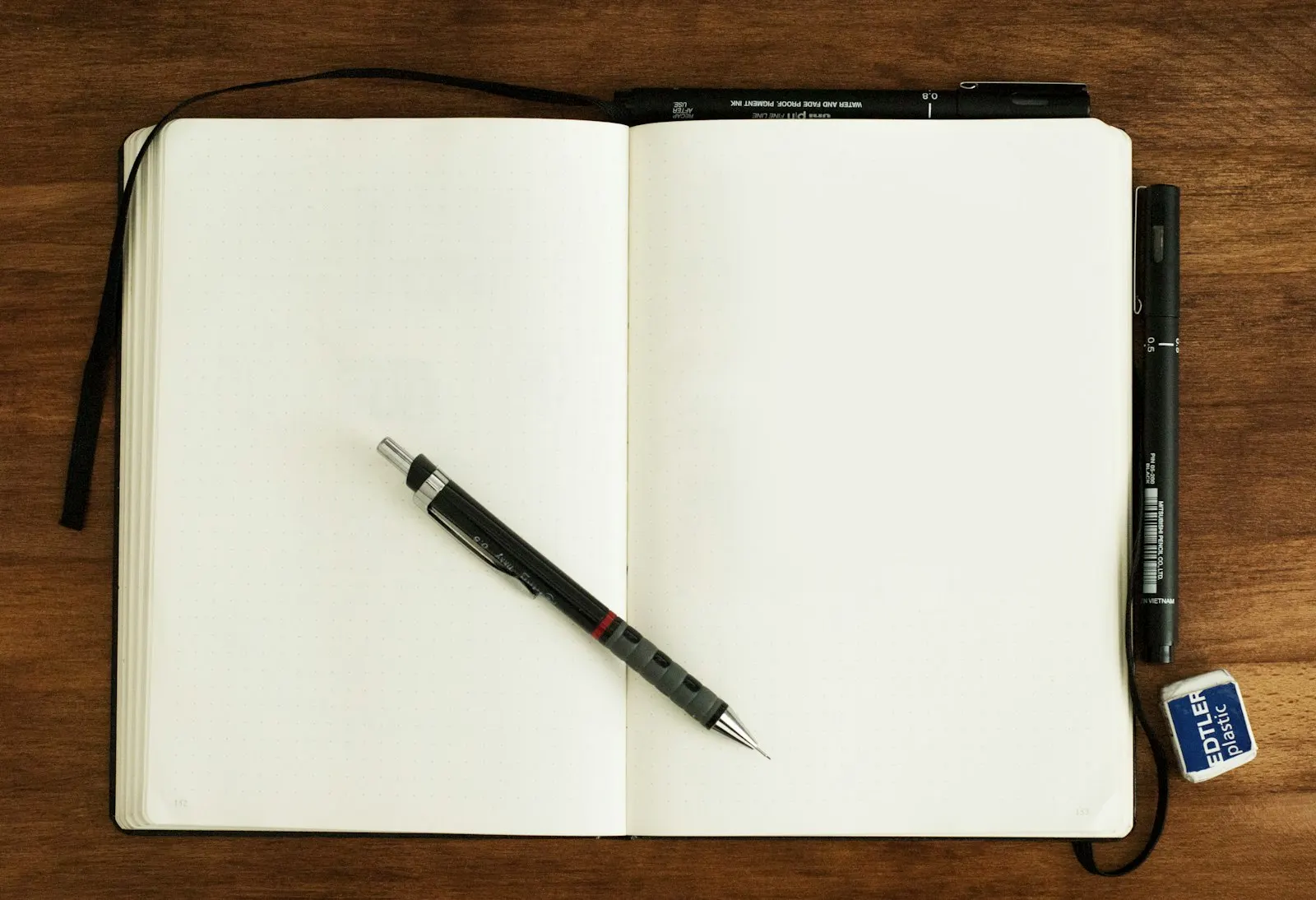 Un carnet vierge ouvert et un crayon posés sur une table en bois