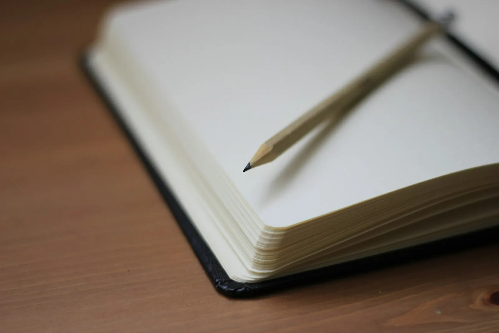 Un crayon à papier posé sur un carnet ouvert aux pages blanches